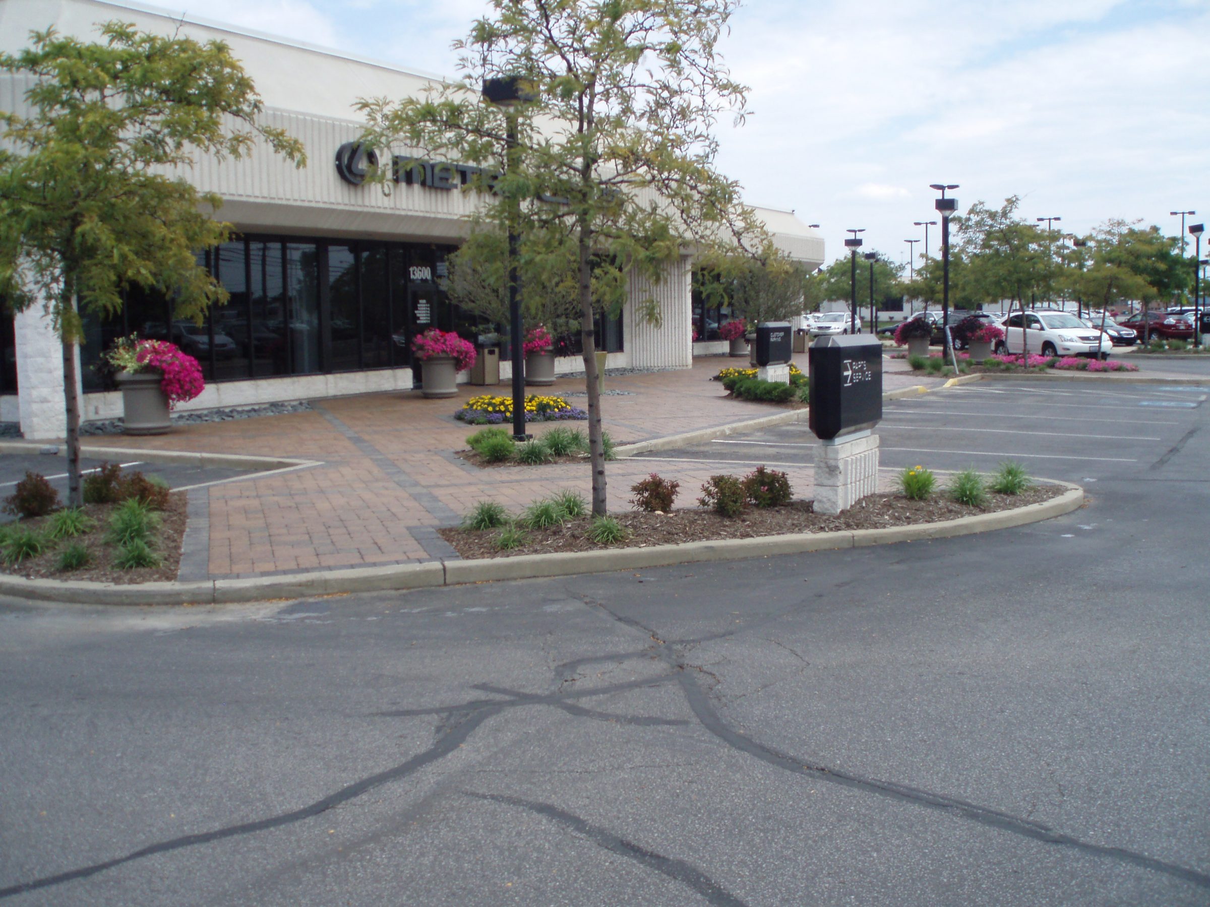 Shopping center entrance with plants and parking lot.