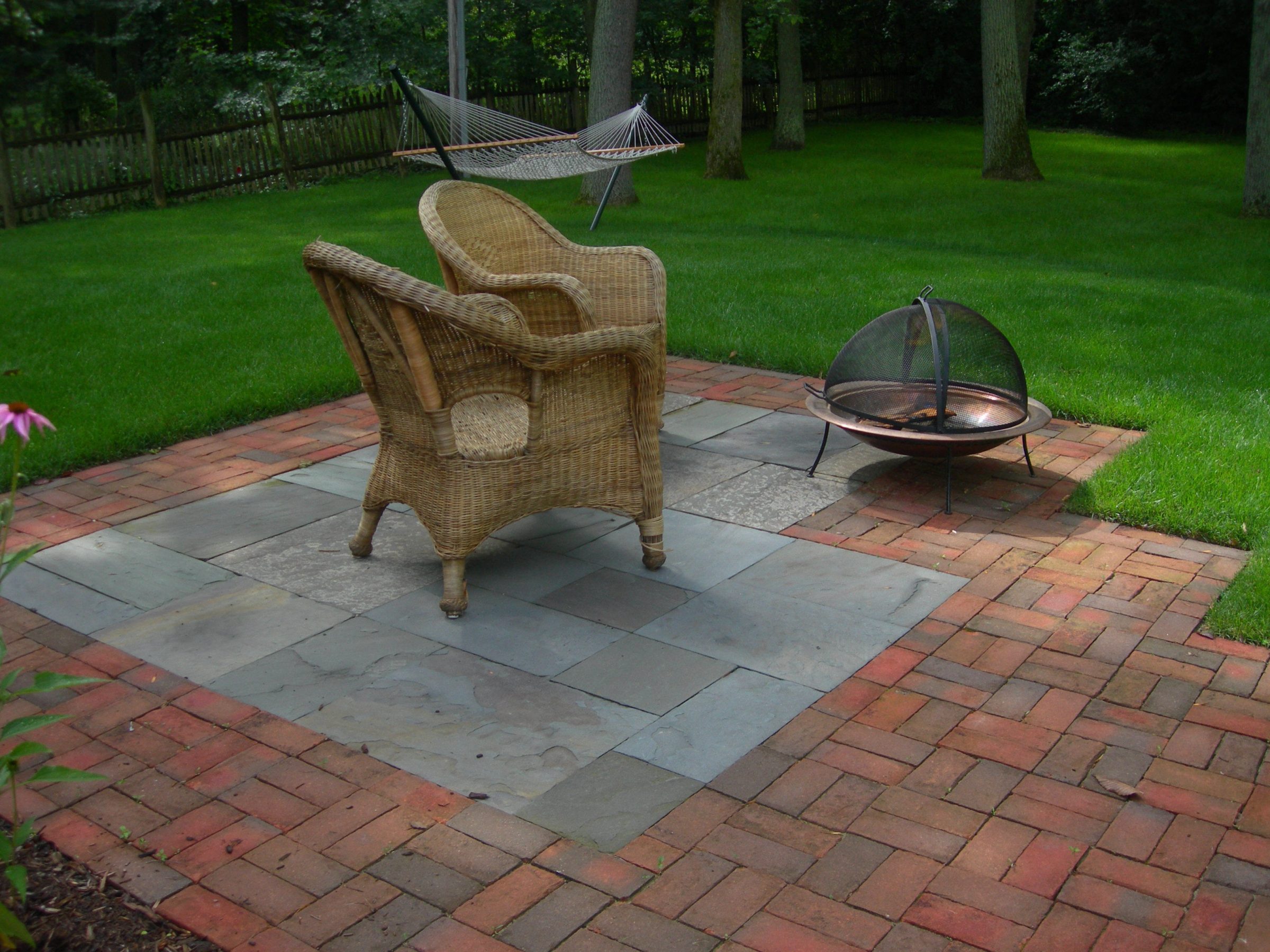 Patio with chair, fire pit, hammock, and lawn.