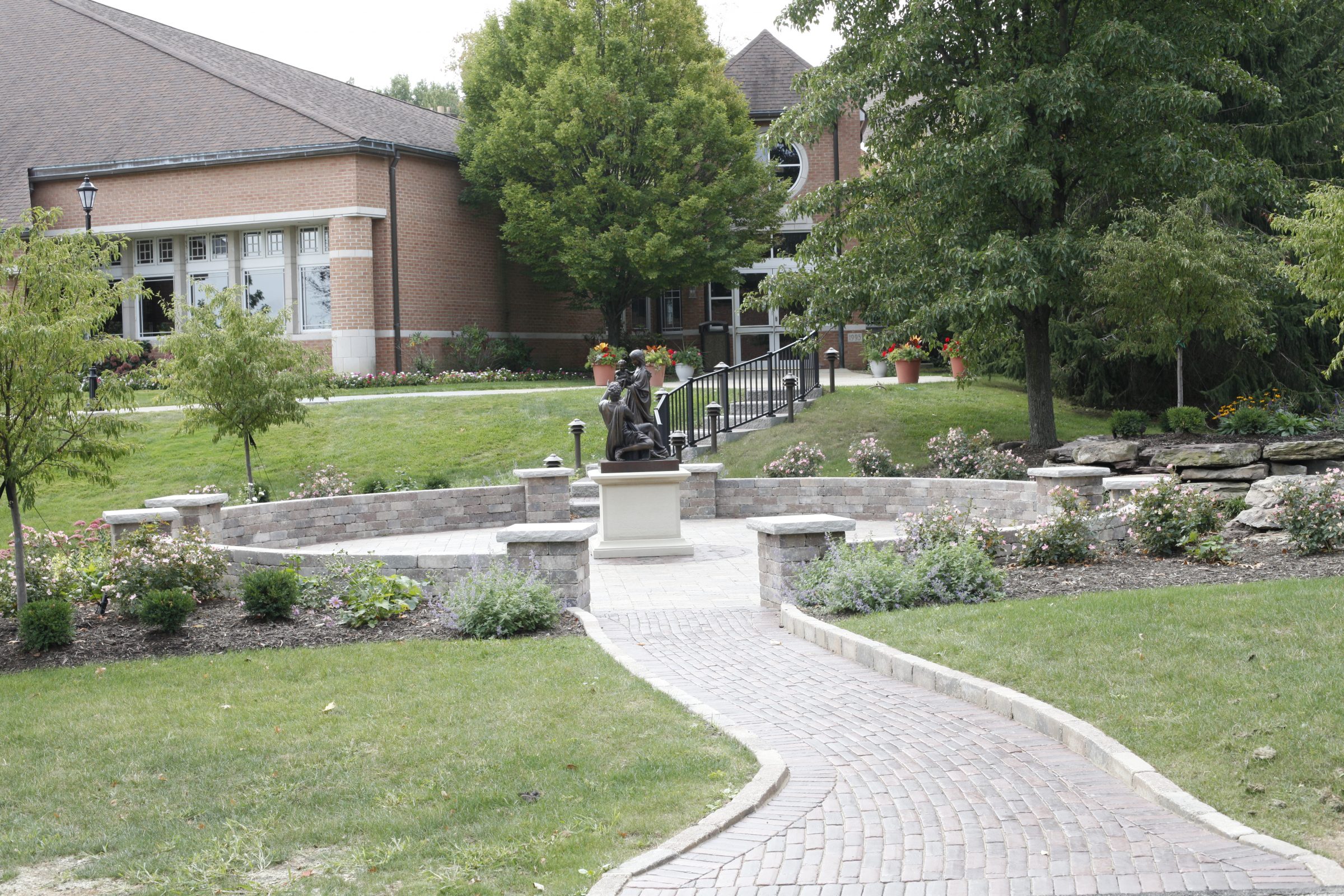 Peaceful garden path with statue and building view.