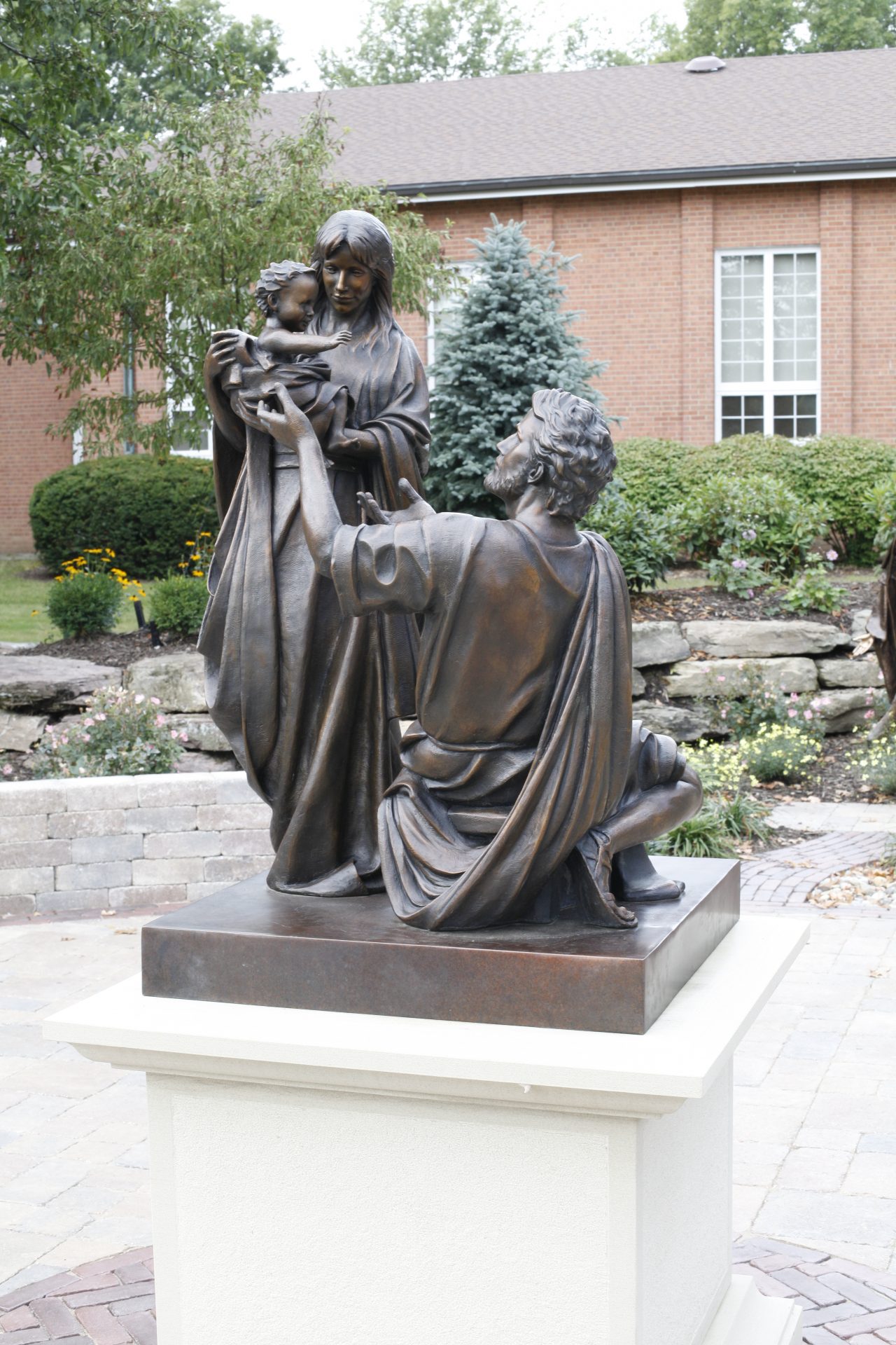 Bronze statue of family with child in garden.