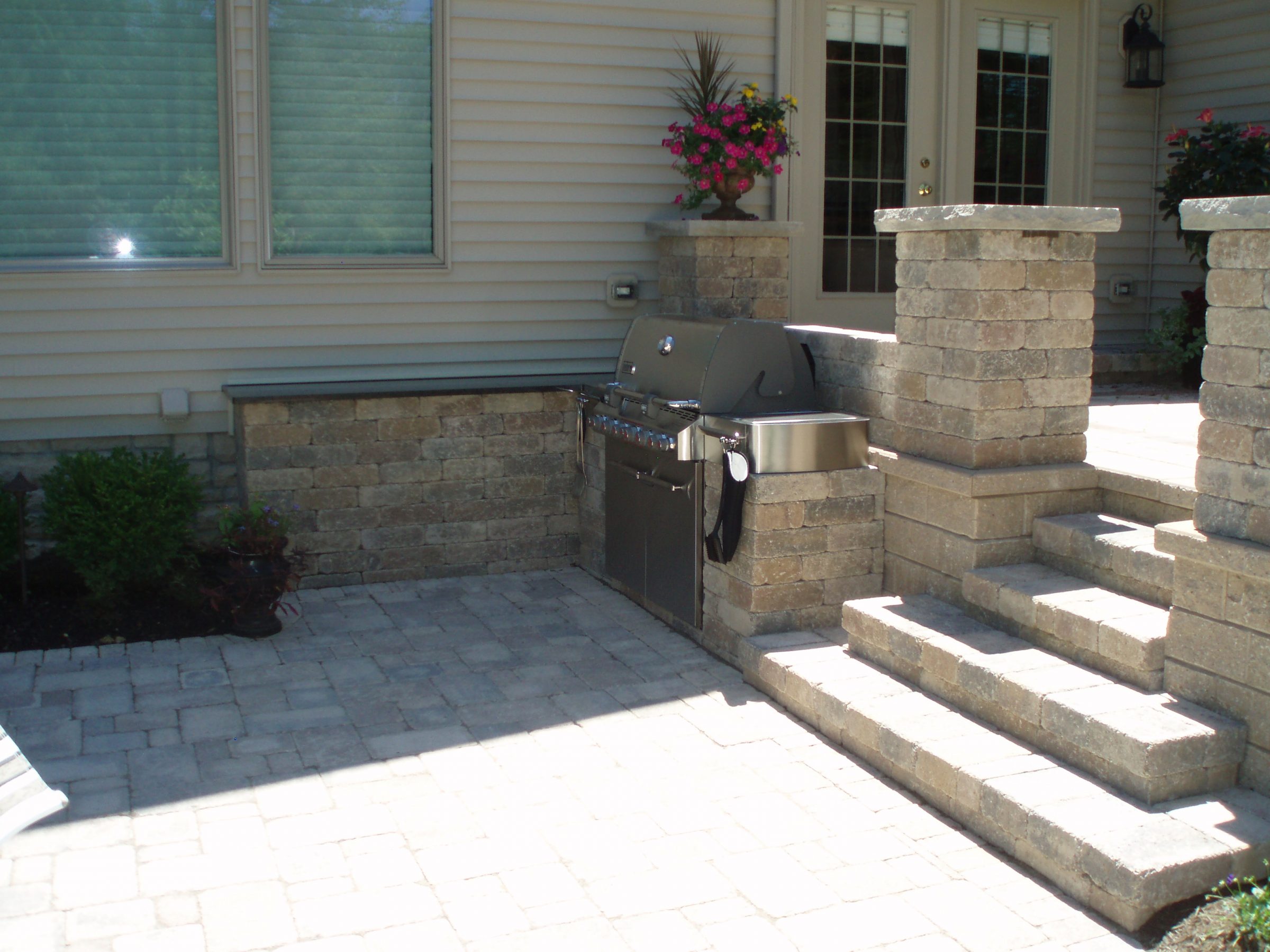 Backyard patio with built-in grill and steps.