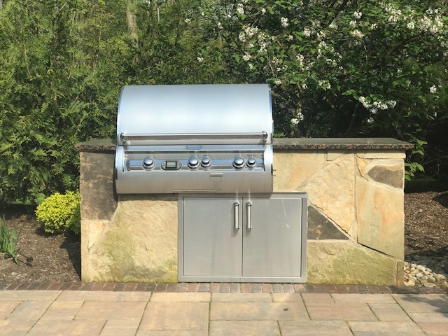 Outdoor stainless steel barbecue grill on stone counter.