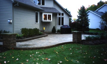 Suburban backyard patio with grill and landscaping.