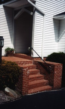 Brick stairs leading to entrance of white building.