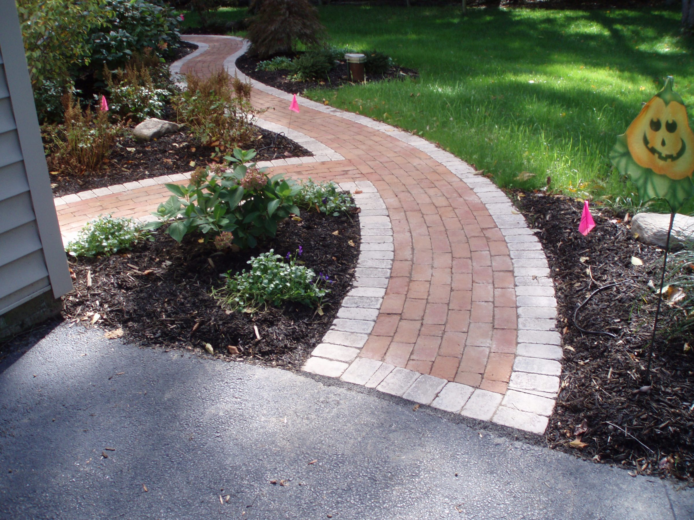 Curved brick garden path in landscaped backyard.