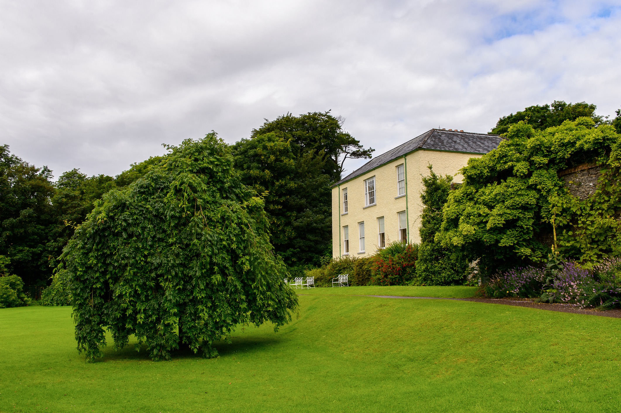 Historic house with lush green garden landscape.