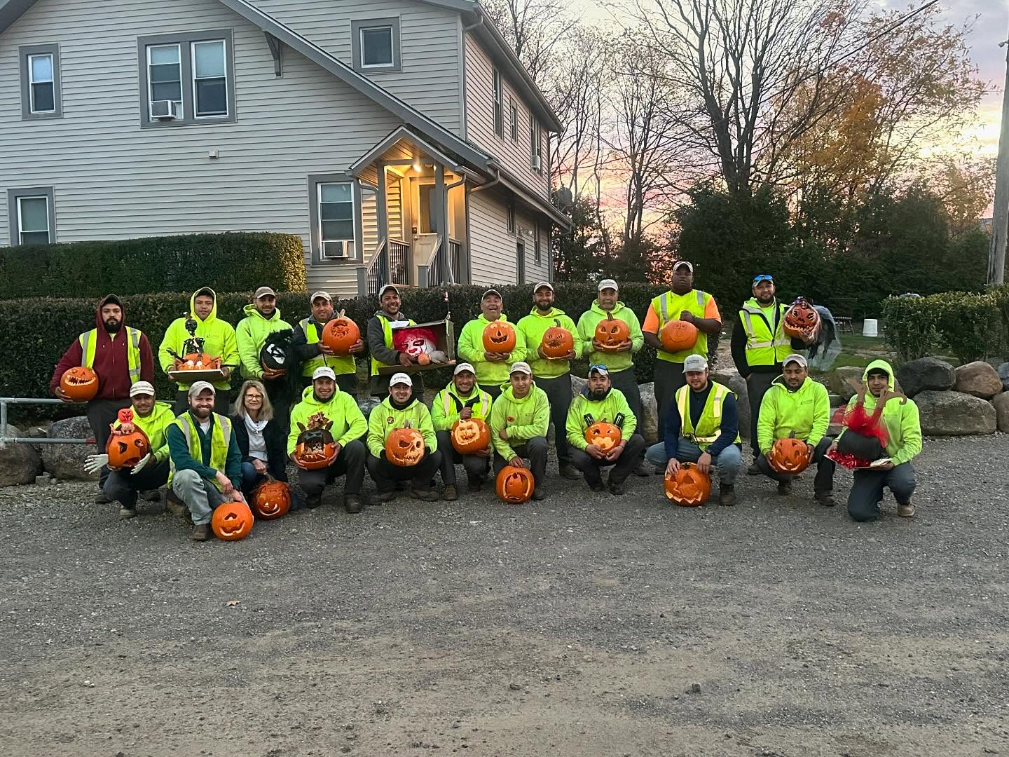 Group with carved pumpkins in front of house.