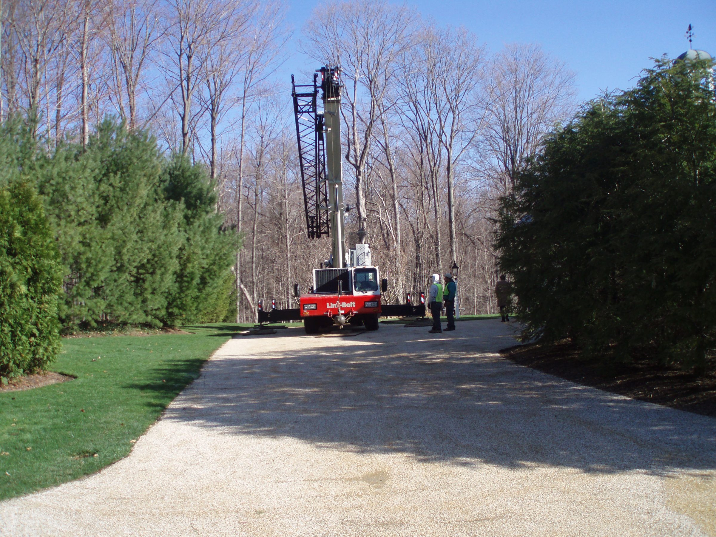 Crane on gravel driveway near trees