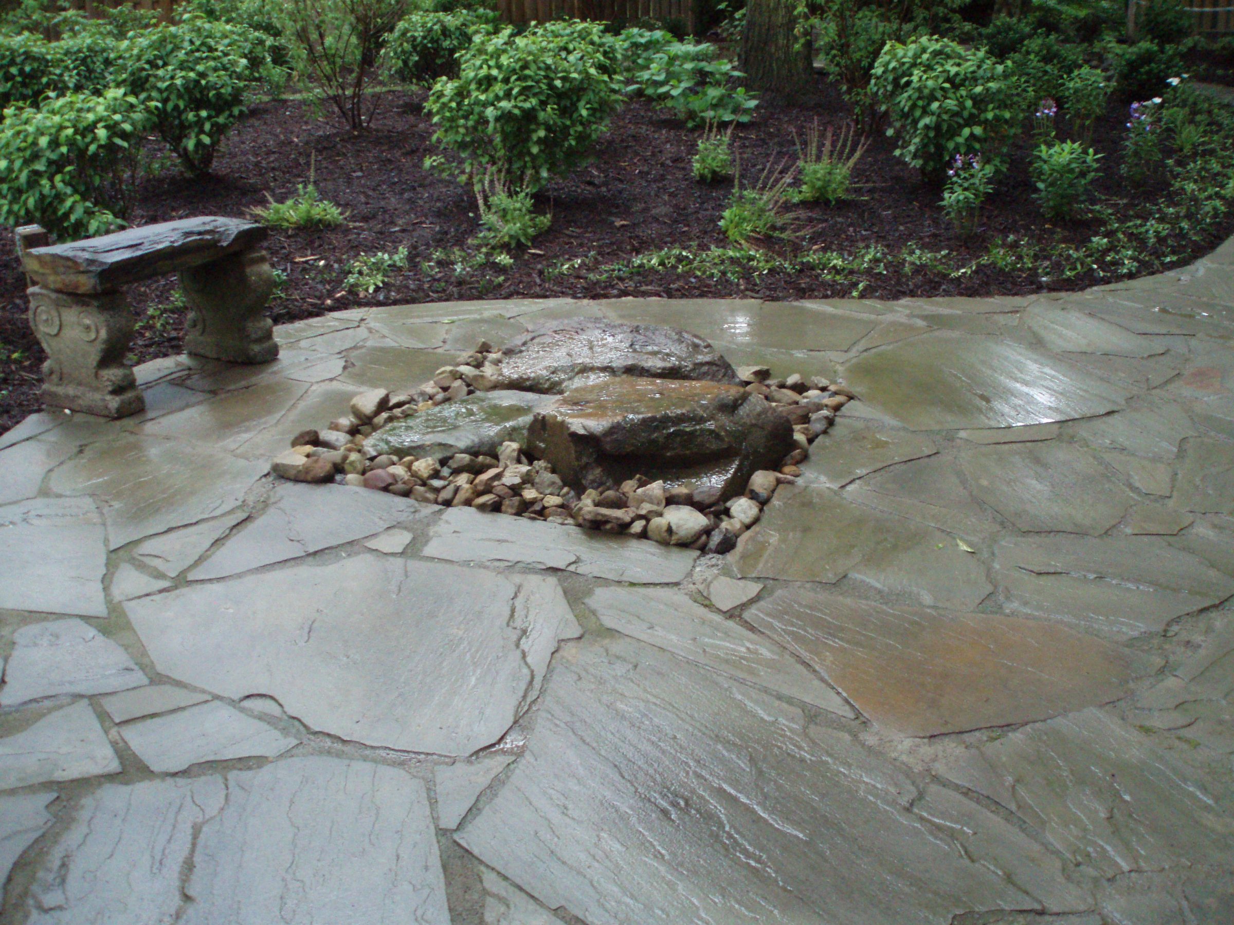 Stone patio with bench and small rock garden.
