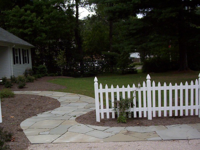 White picket fence along winding stone pathway in yard.