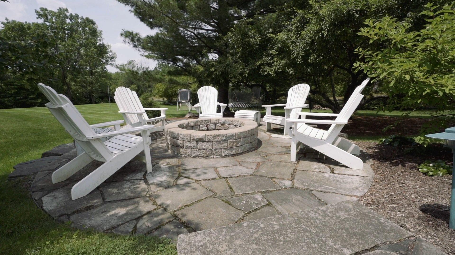 Outdoor fire pit with white chairs on patio