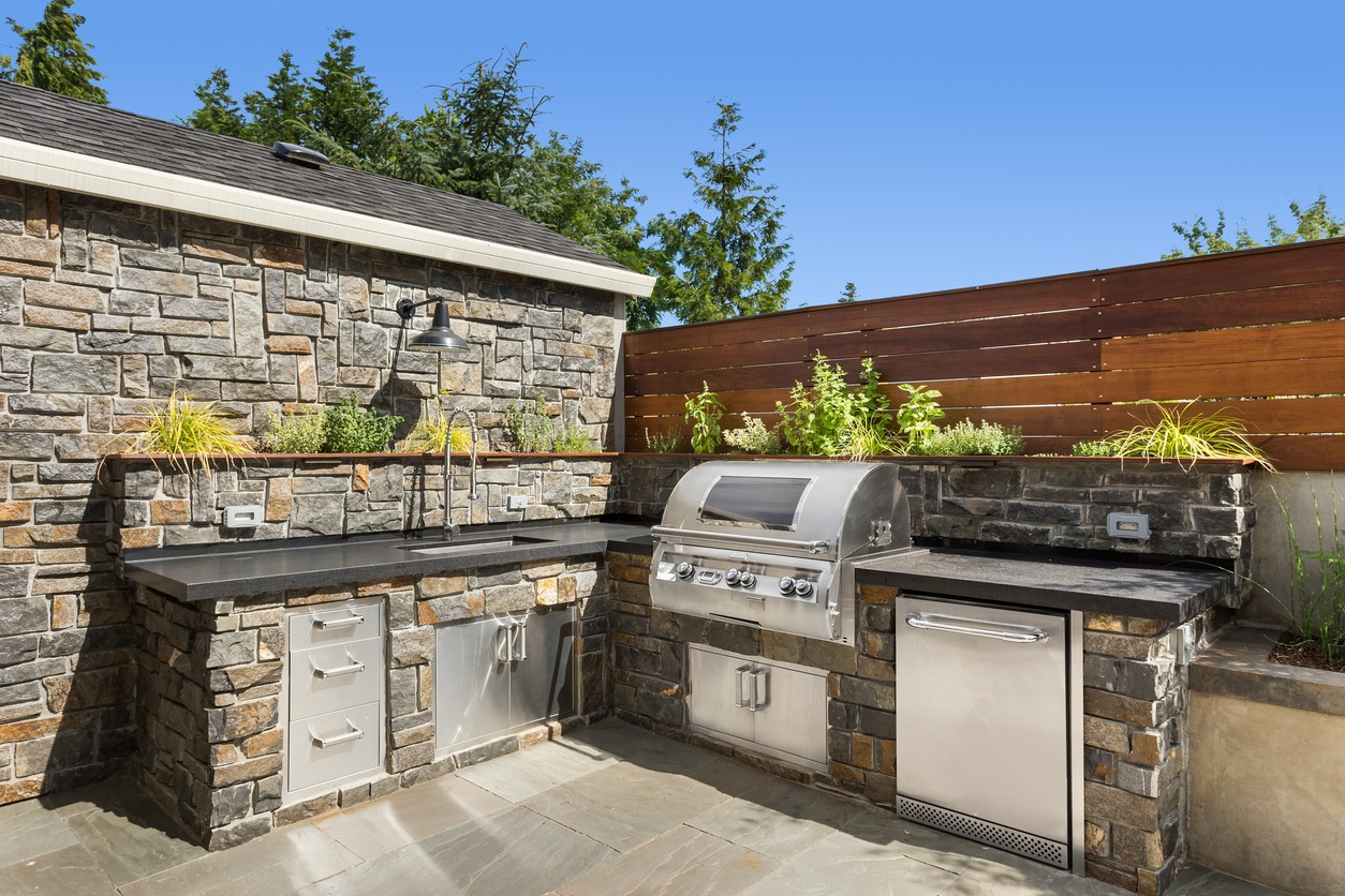Outdoor kitchen with grill and stone countertops.