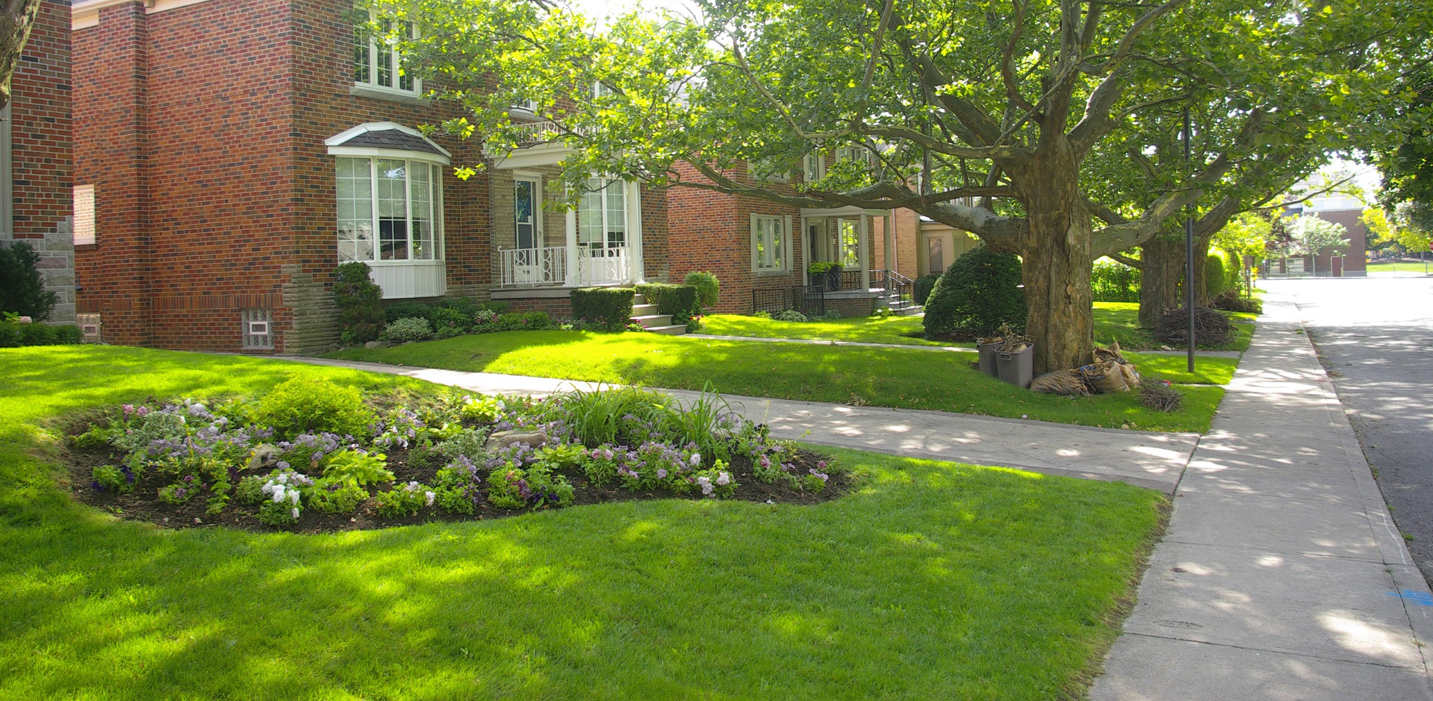 Brick house with landscaped front yard and sidewalk.