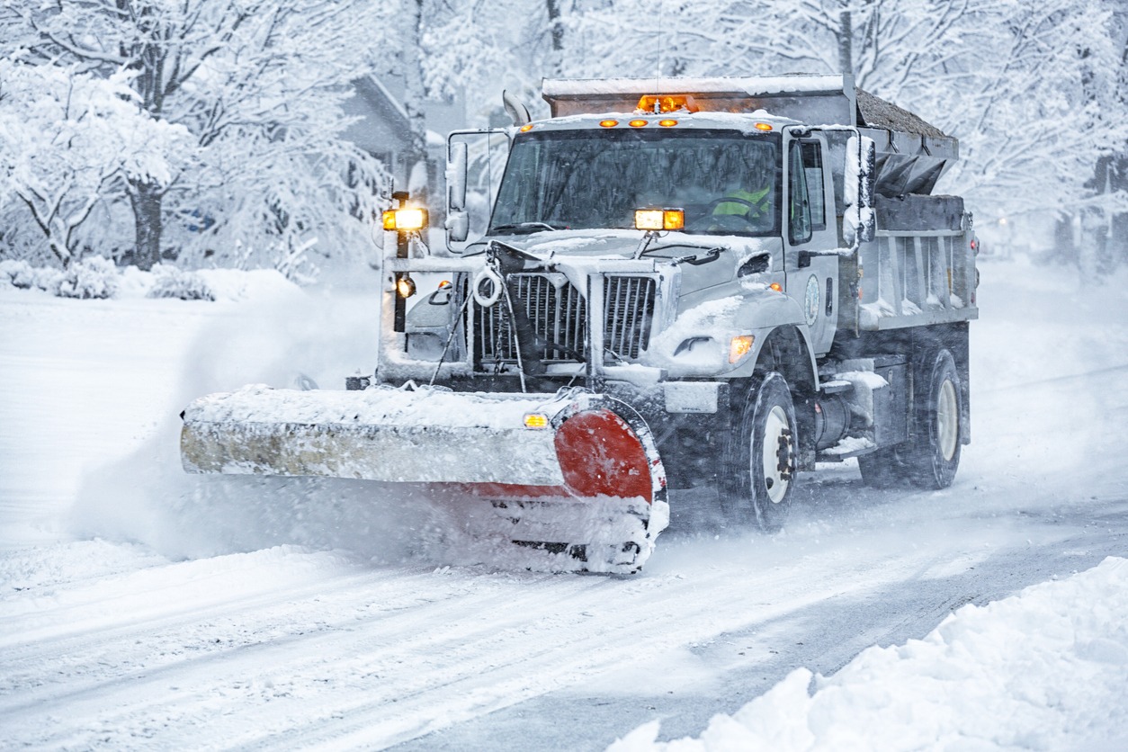 Snowplow clearing snowy road in winter storm.