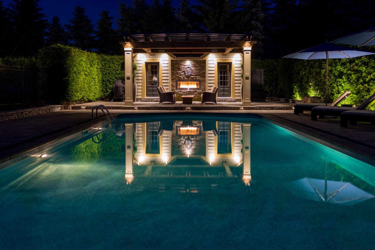 Luxurious backyard pool with illuminated gazebo at night.