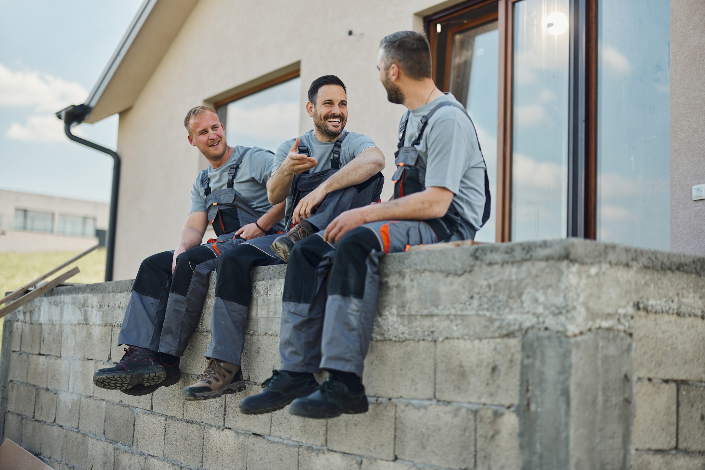 Construction workers chatting on a building site wall.