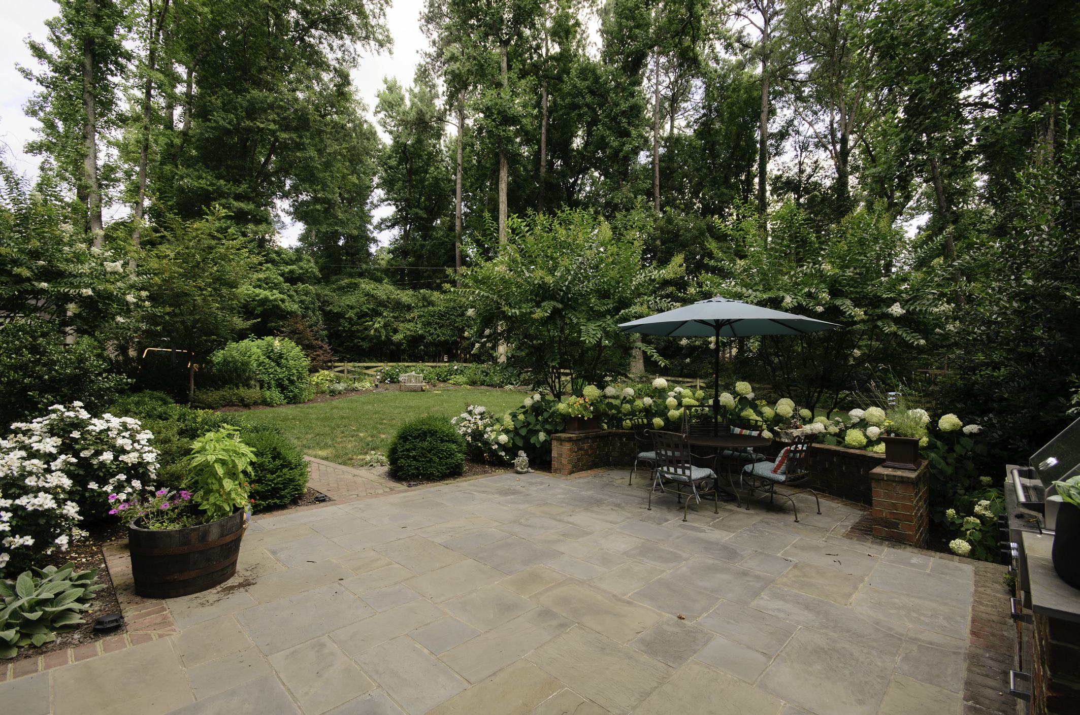 Backyard with patio, greenery, and outdoor dining area.