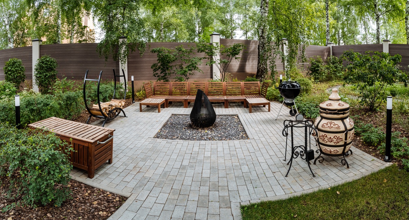 Outdoor garden with benches and fireplace centerpiece.