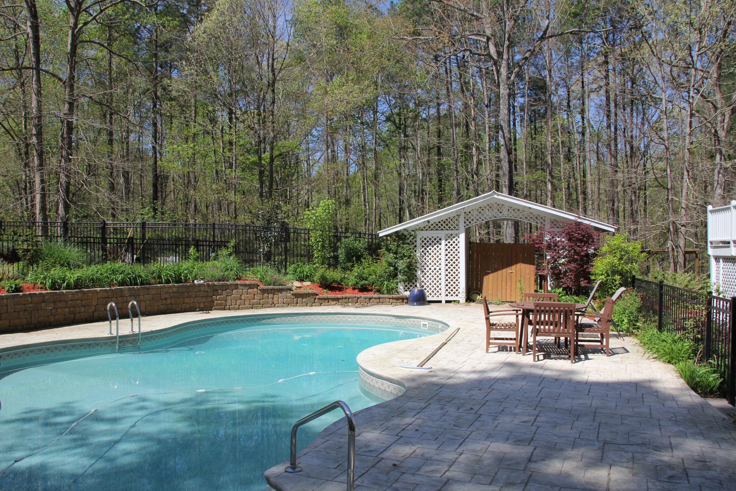Backyard pool with seating area and trees.