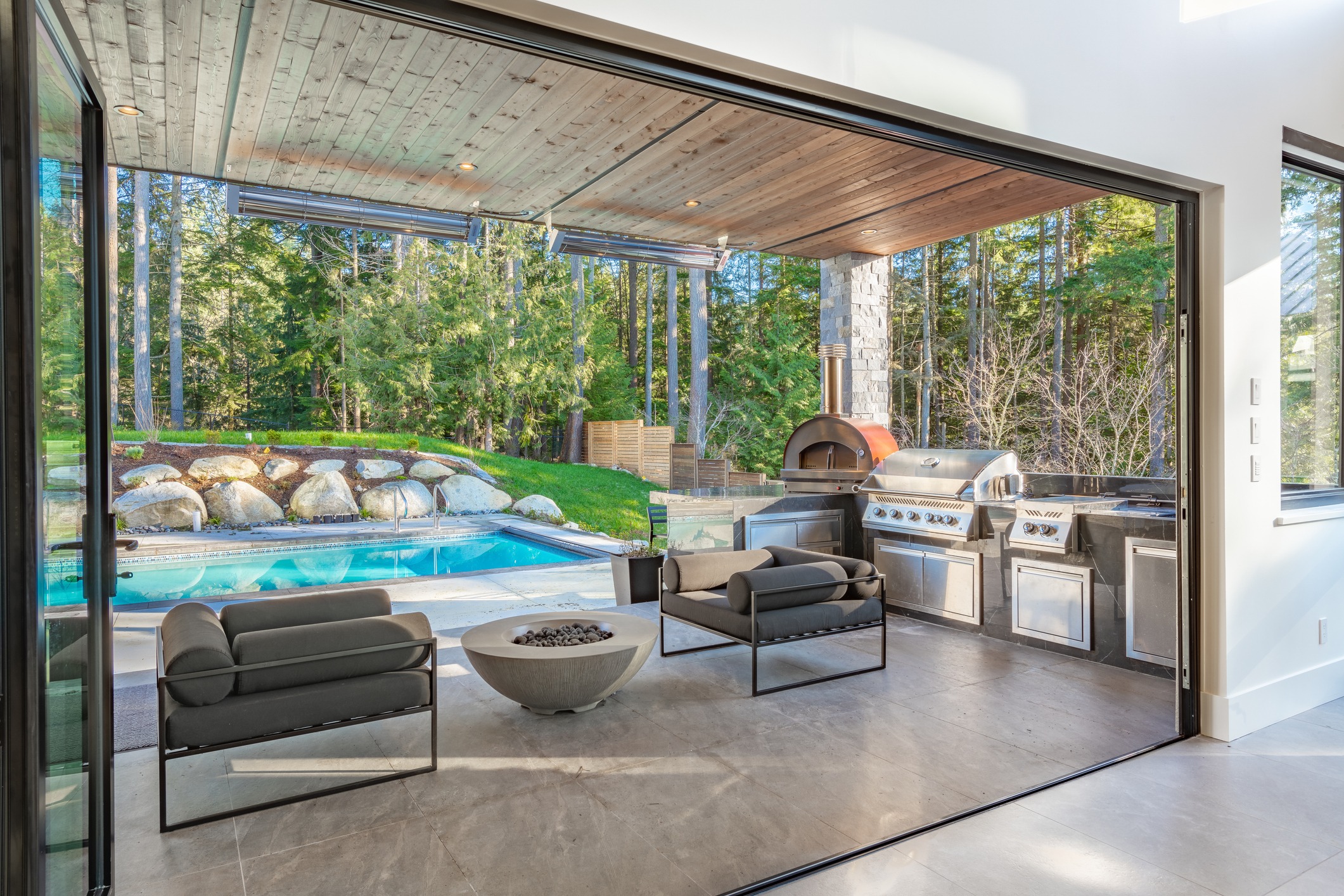 Modern outdoor patio with pool and grill area.