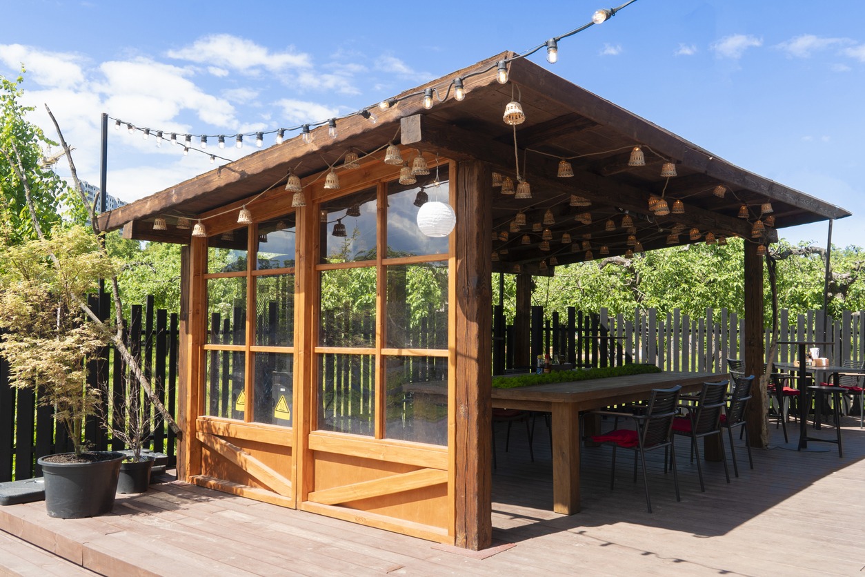 Wooden patio with chairs and hanging lights outdoors.