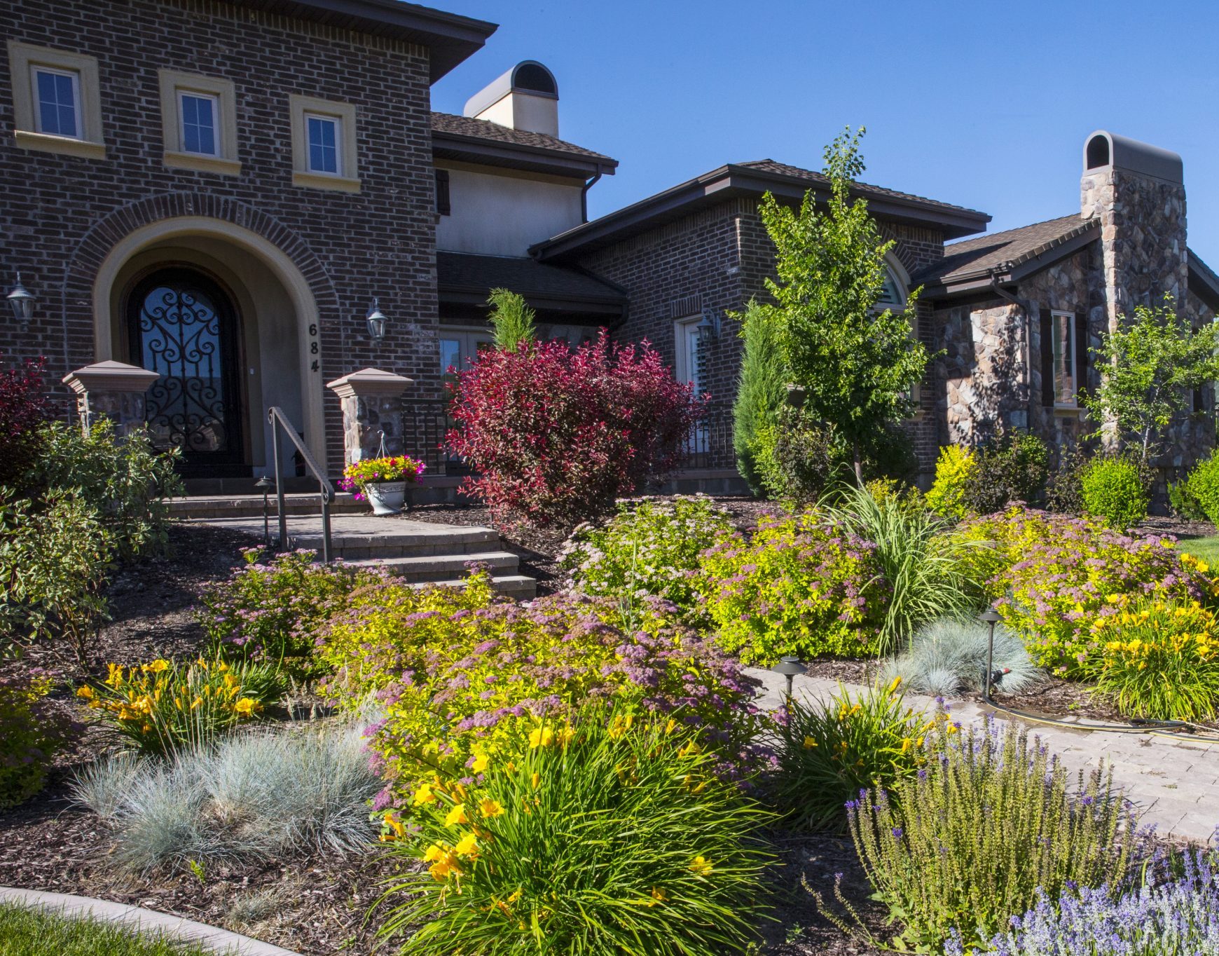 Colorful garden in front of a brick house.