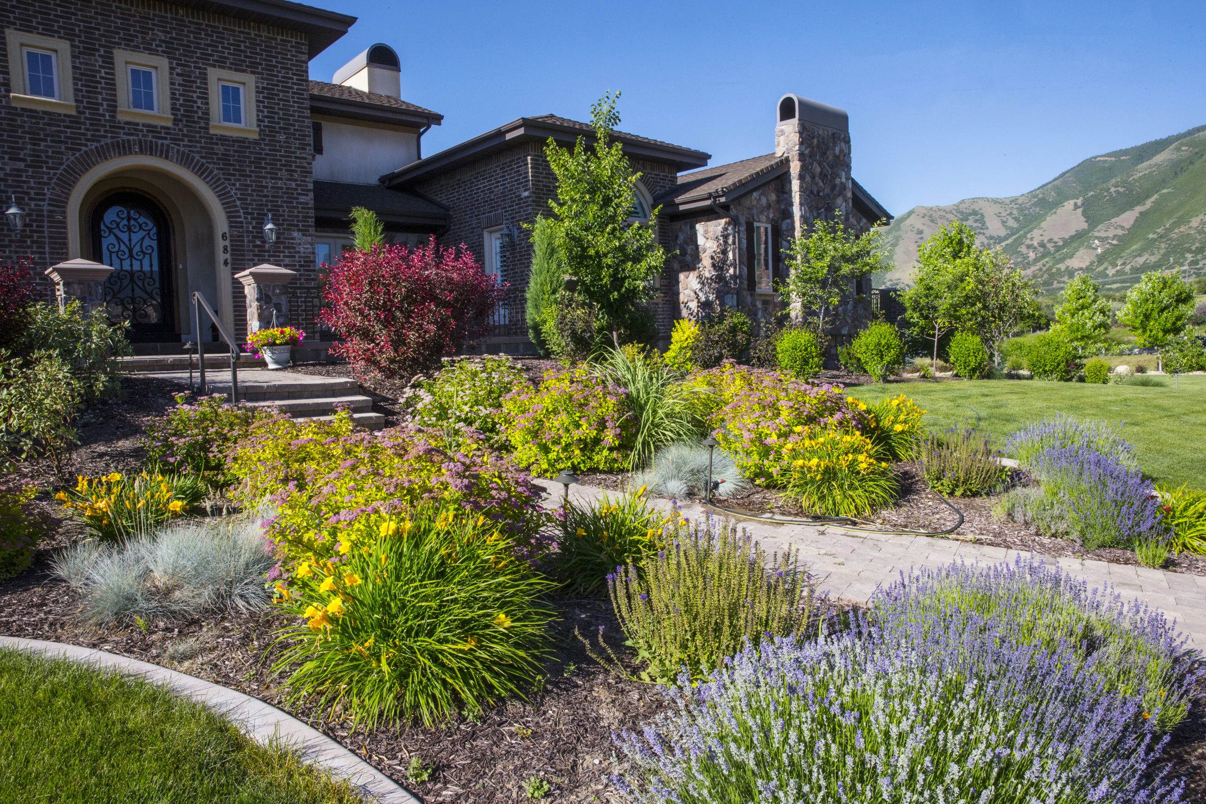 Colorful garden in front of a brick house.