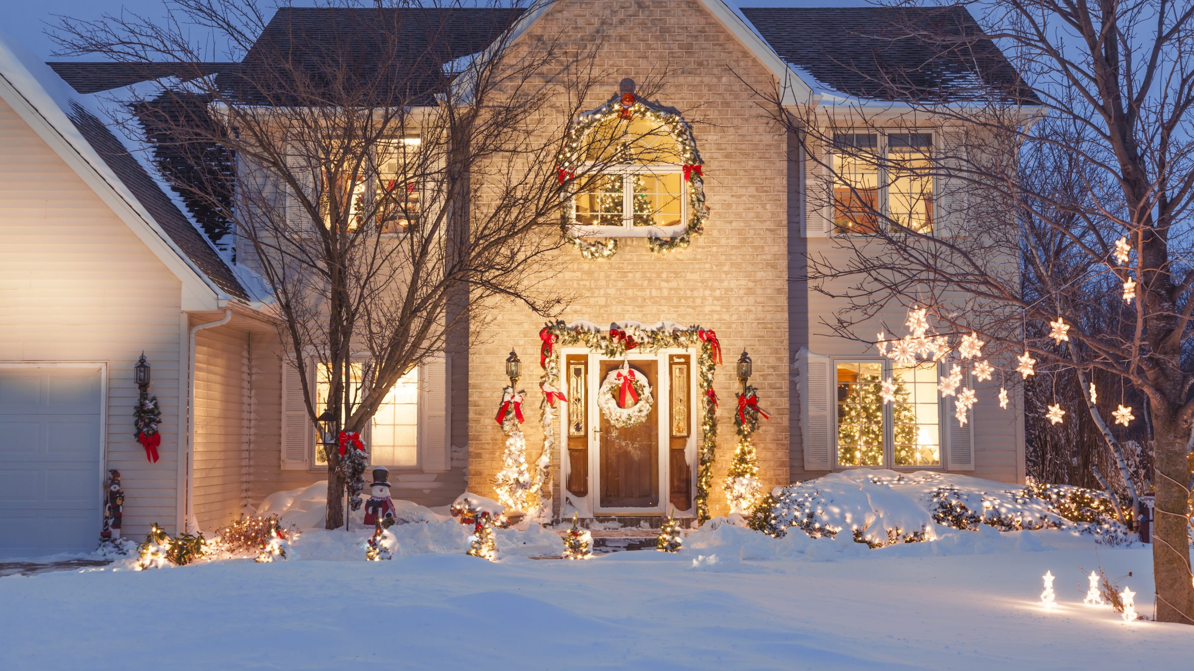 Snowy house with Christmas lights and decorations.