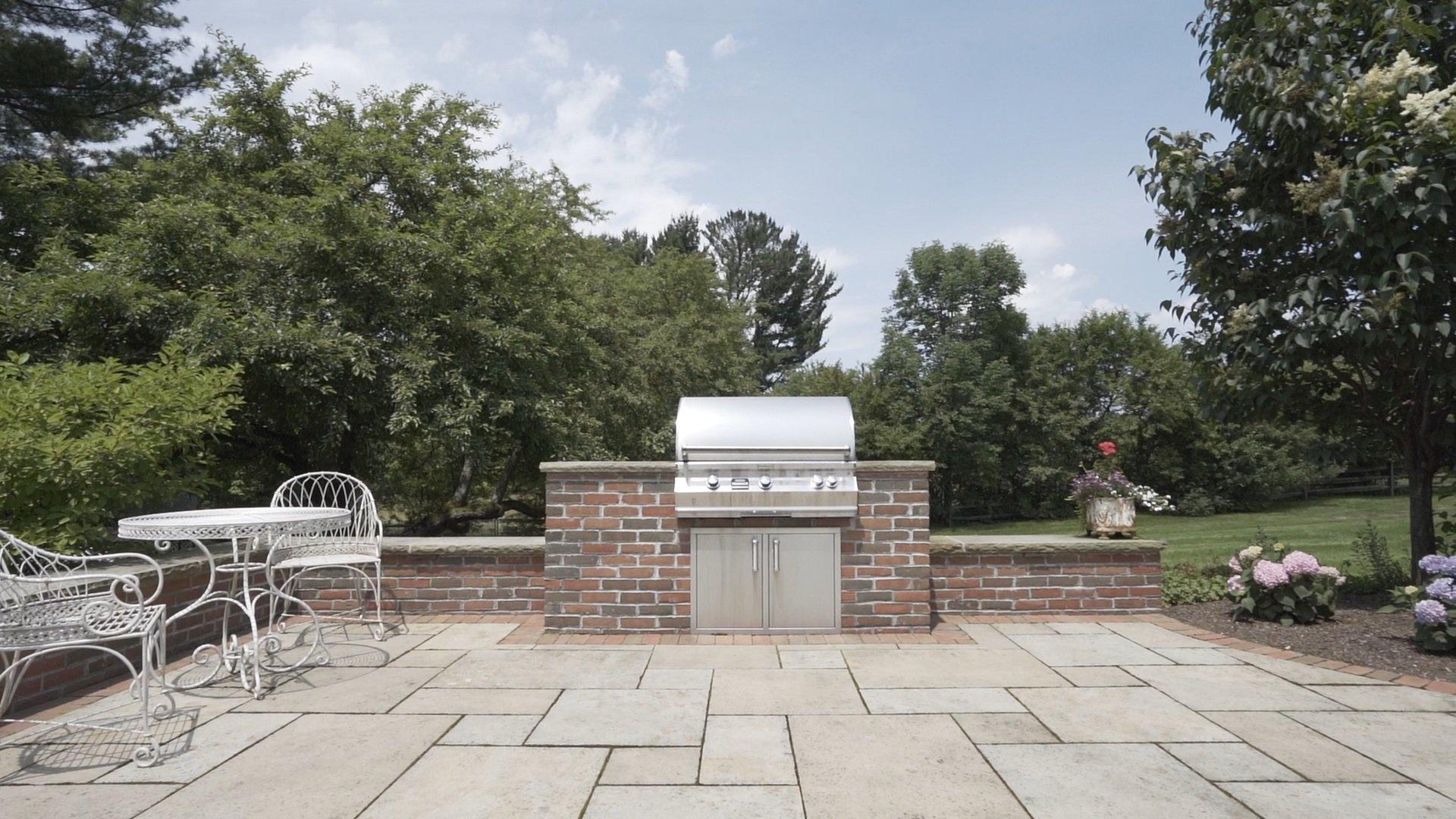 Stone patio with barbecue and metal table set.